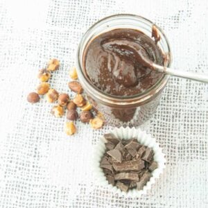 homemade nutella in jar with whole hazelnuts and chopped chocolate