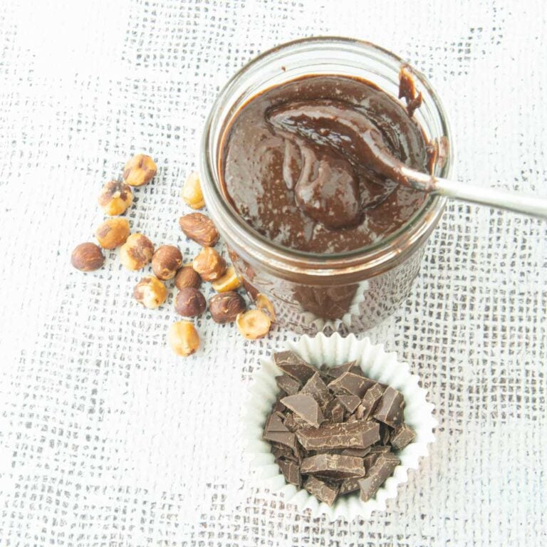 homemade nutella in jar with whole hazelnuts and chopped chocolate