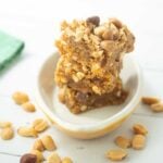 peanut butter blondies stacked in dish with whole peanuts