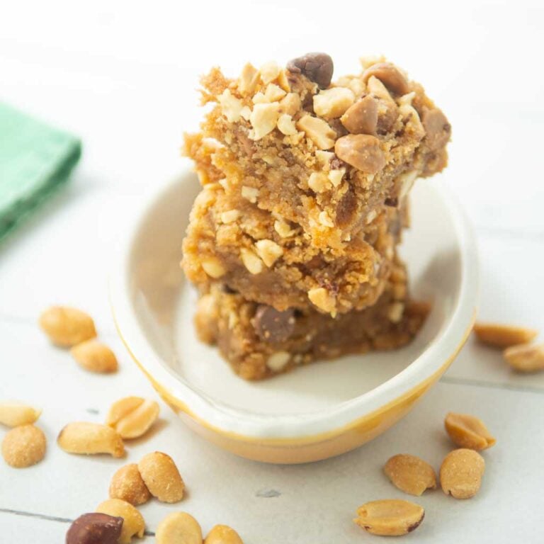 peanut butter blondies stacked in dish with whole peanuts