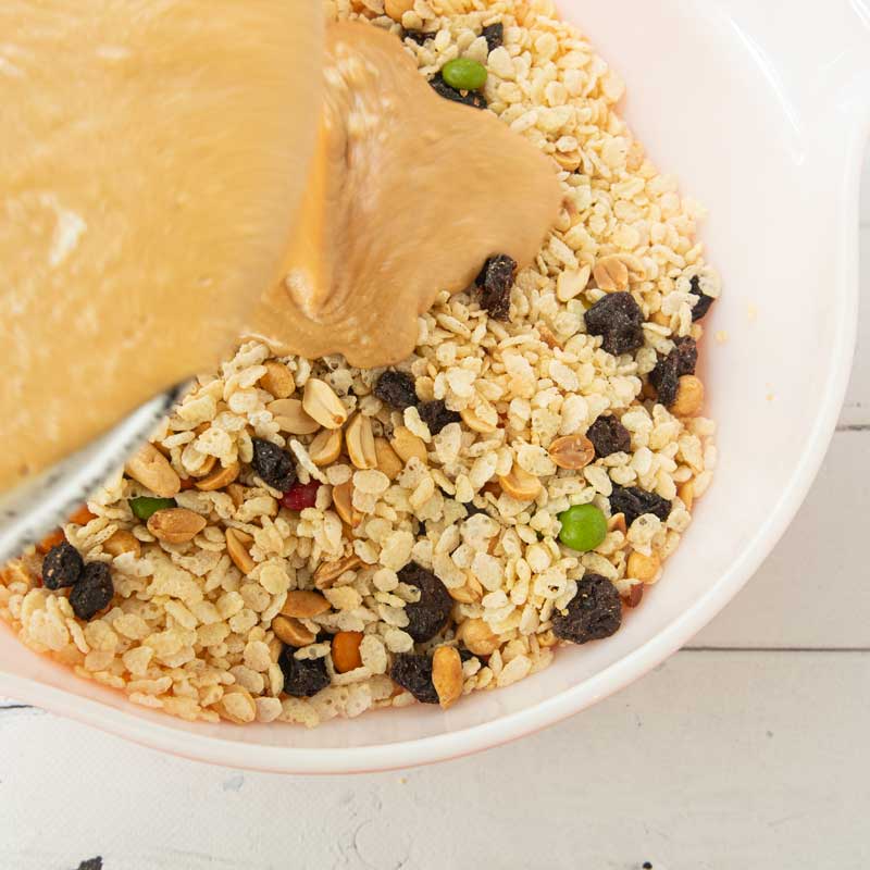 pouring peanut butter over rice krispies