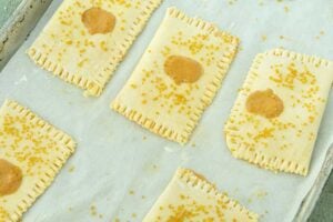 adding sprinkles to the tops of pumpkin hand pies