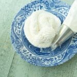 whipped cream frosting on plate next to piping bag