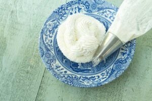 whipped cream frosting on plate next to piping bag