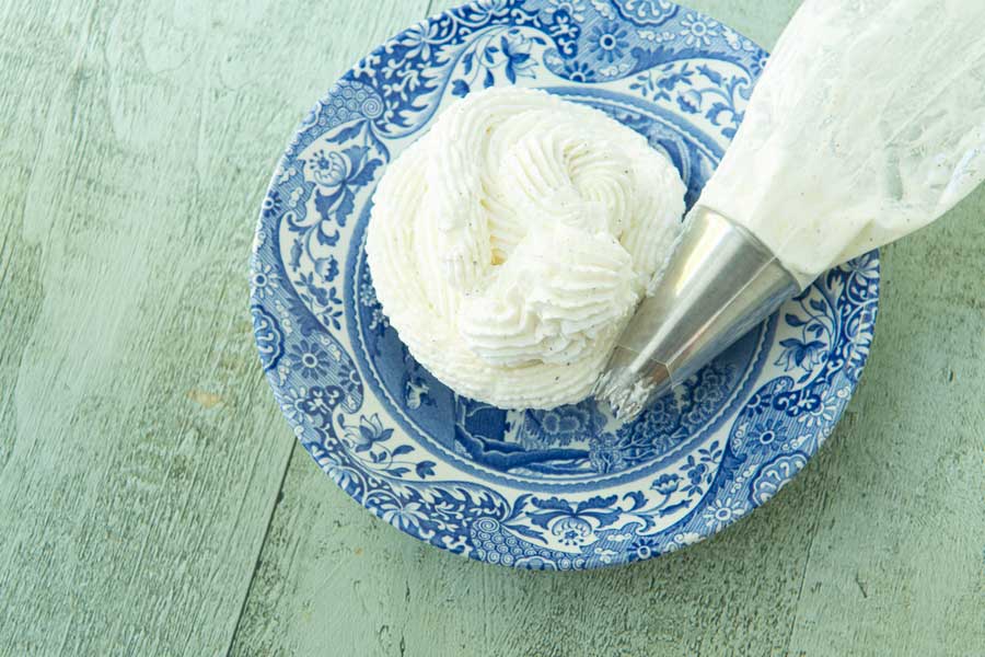whipped cream frosting on plate next to piping bag