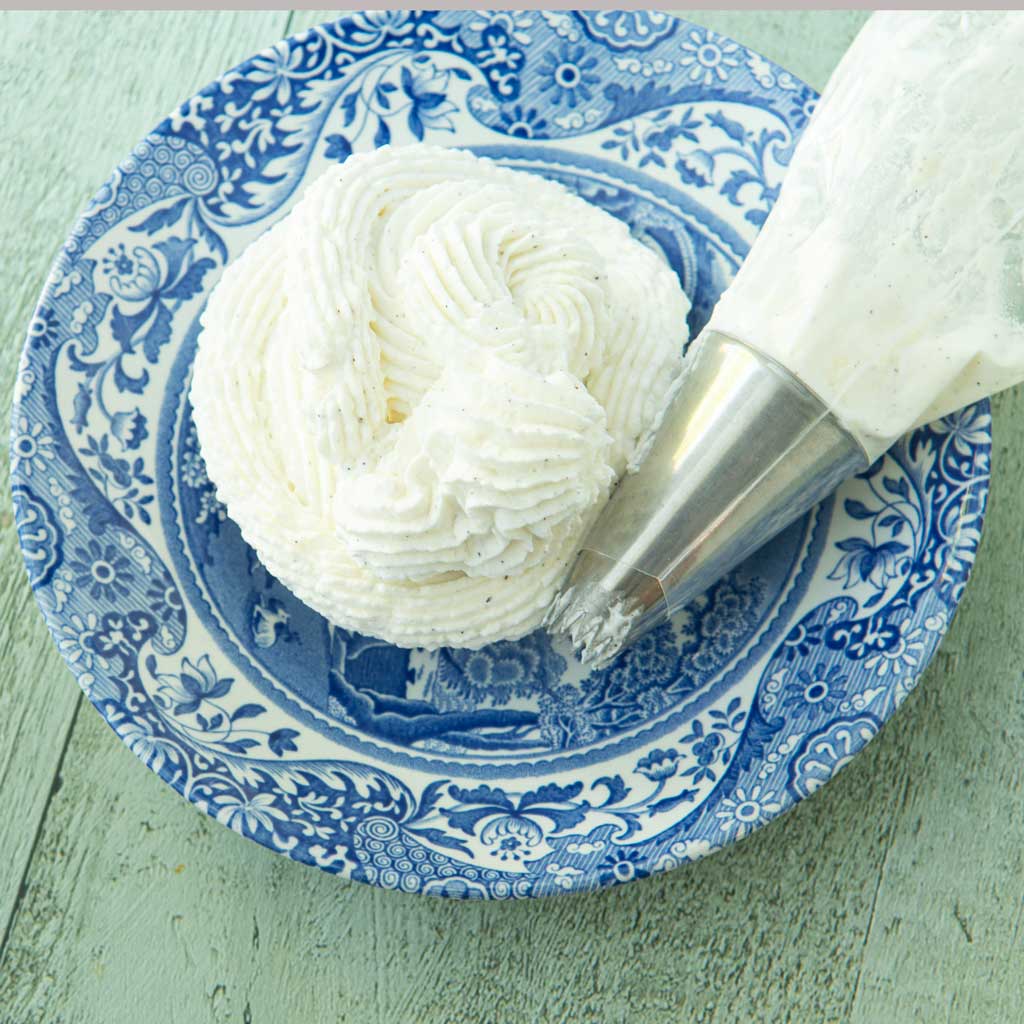 whipped cream frosting on plate next to piping bag