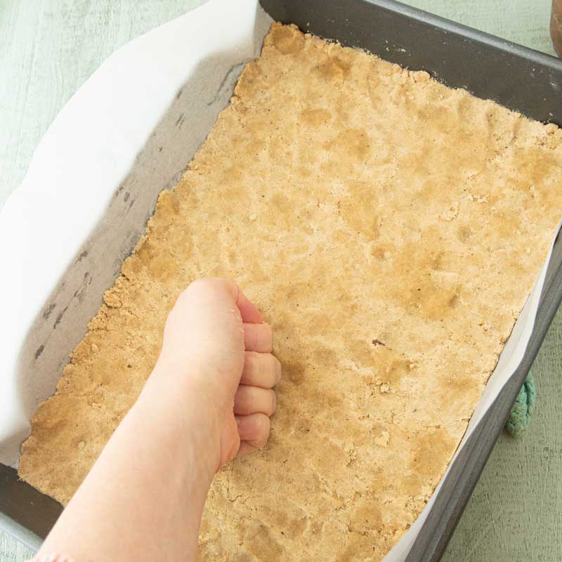 using knuckles to press dough into pan