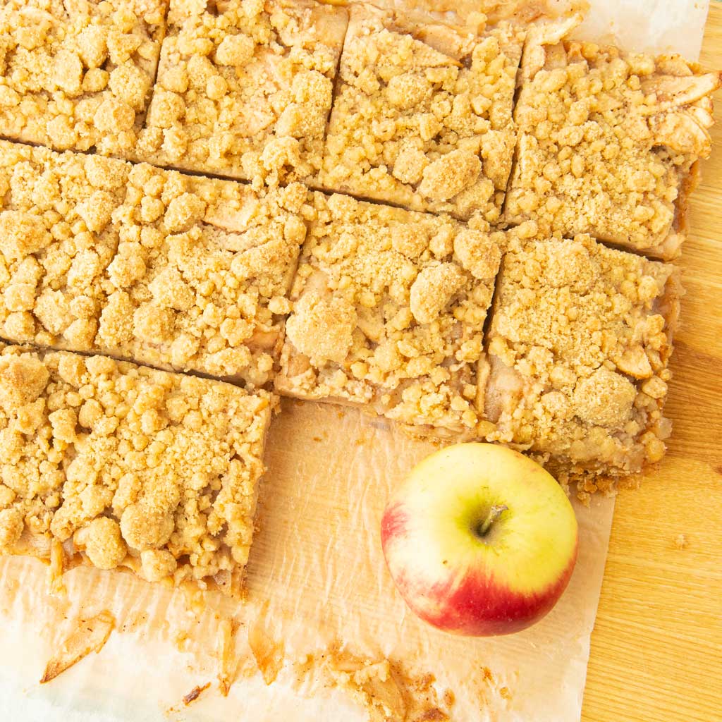 apple crumble bars on cutting board with whole apple