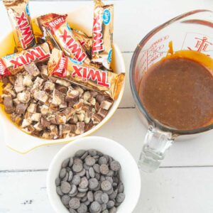 chopped Twix, Twix in wrappers, caramel sauce, and chocolate chips