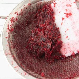 pressing cranberry pulp through strainer with dough scraper