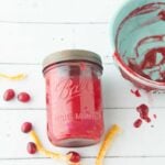 cranberry curd in jar next to bowl, candied orange peel and whole cranberries