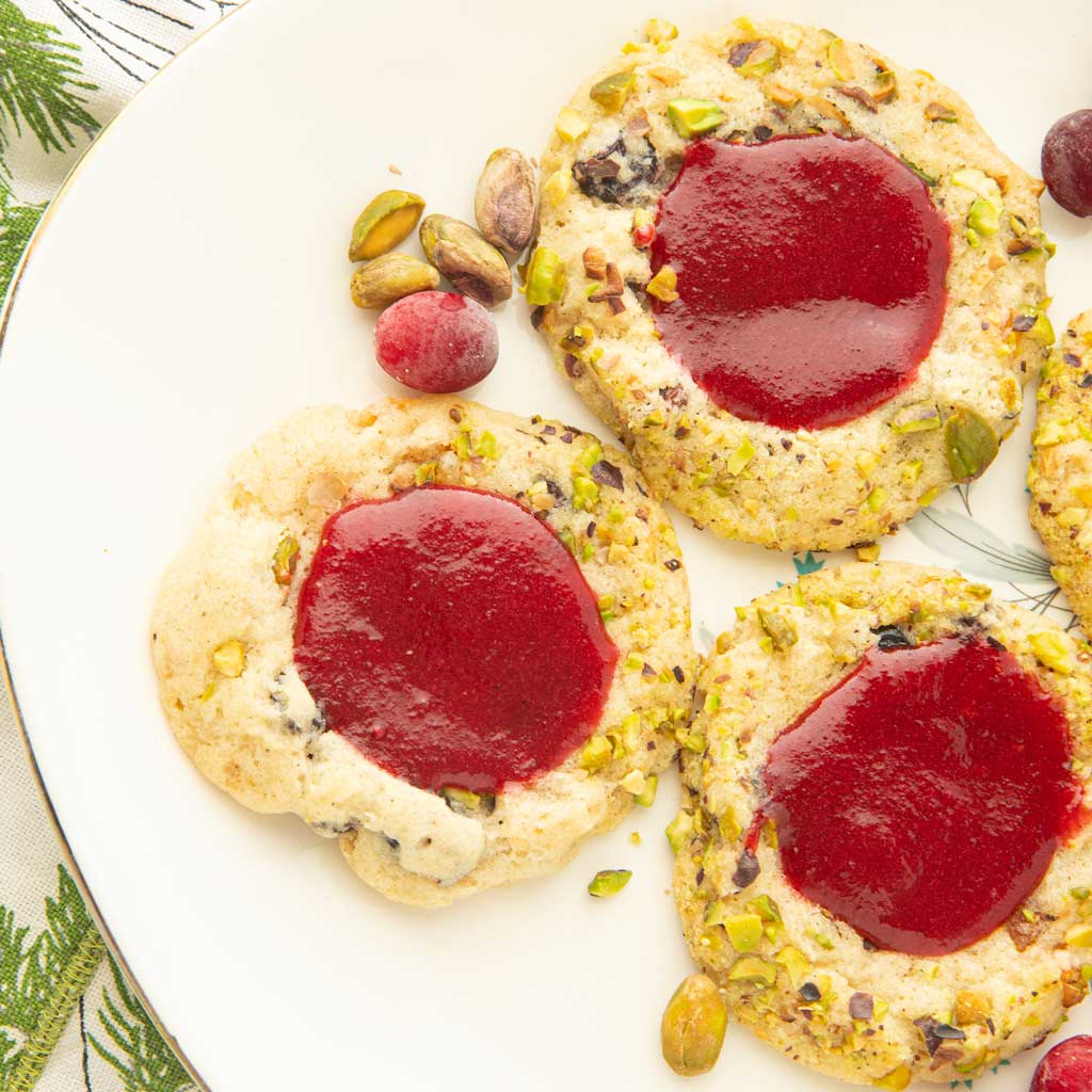 cranberry cookies on plate with whole pistachios and cranberries
