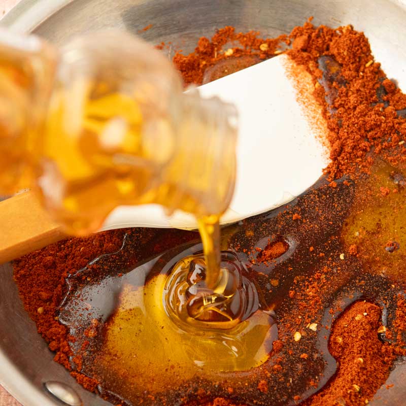 adding honey to chiles in pan