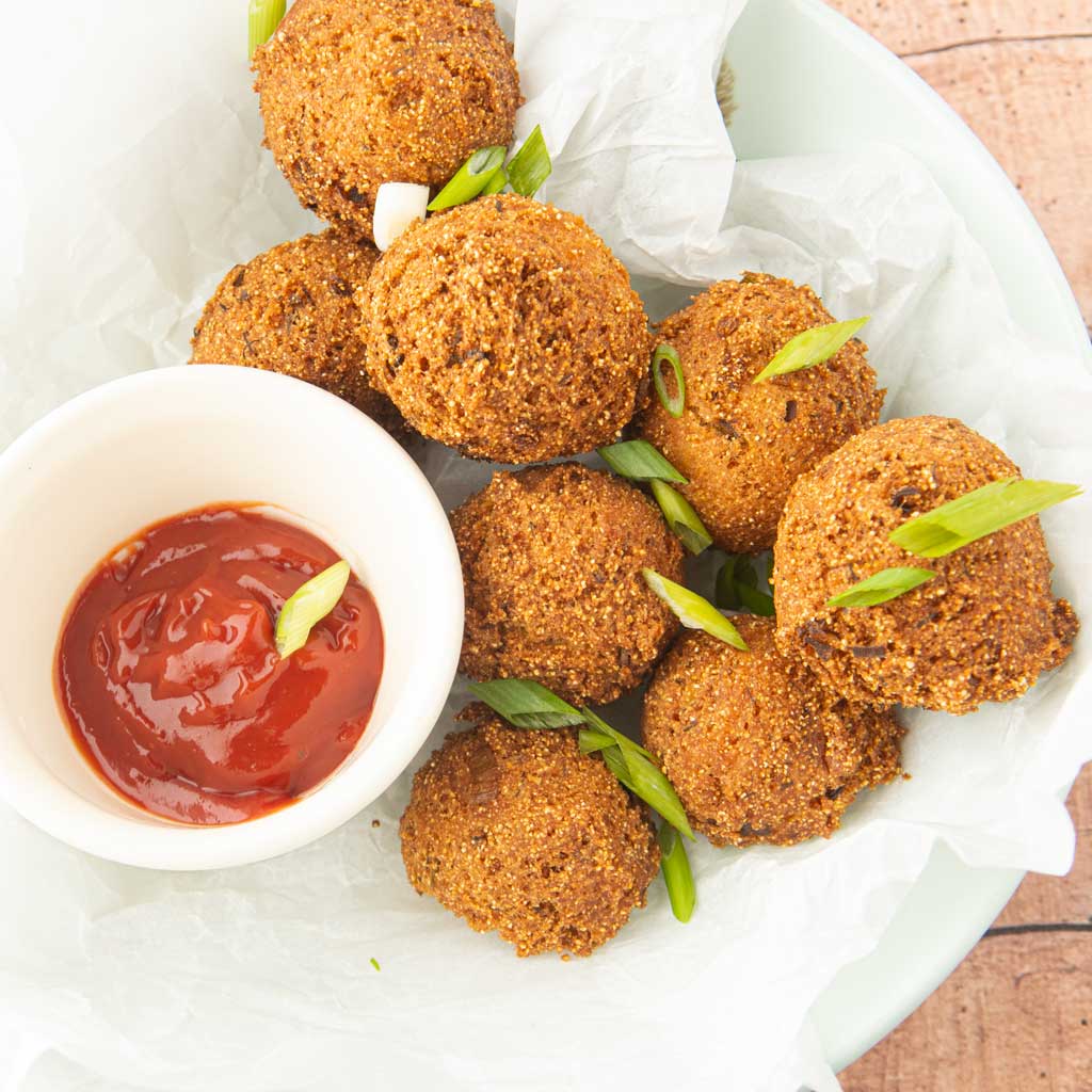 hushpuppies in bowl with ketchup and green onions