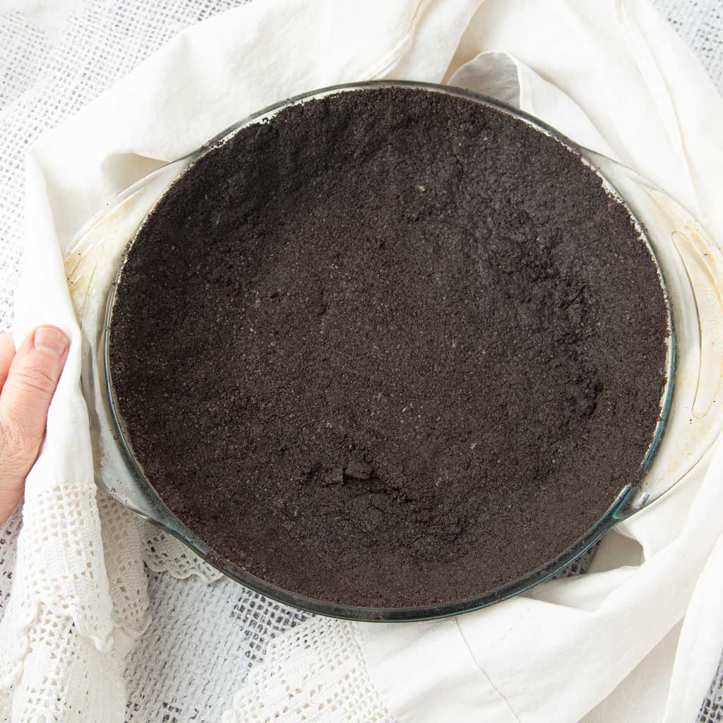 hand holding oreo pie crust in pie plate