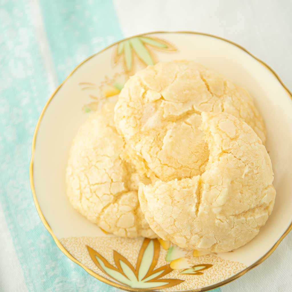 lemon crinkle cookies on plate, one with a bite out of it