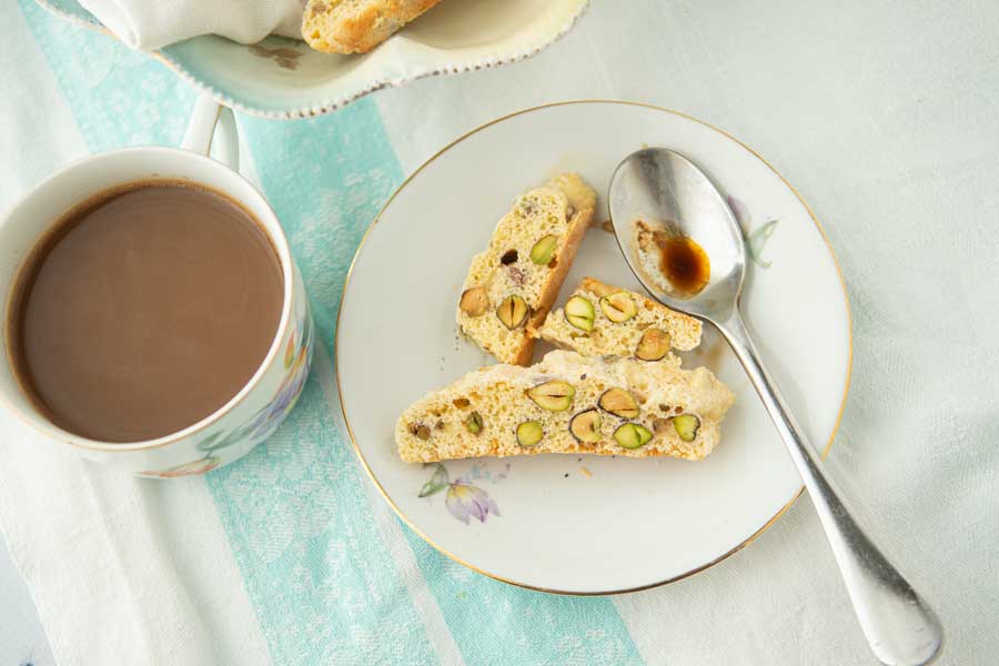 biscotti on plate with spoon and a cup of coffee