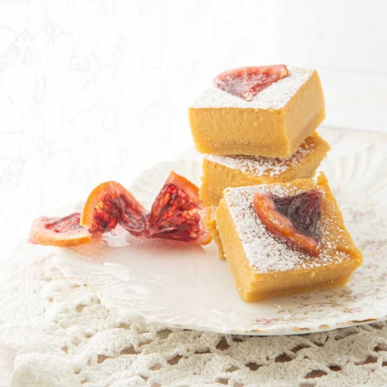 stack of orange bars topped with candied orange slices next to candied orange slice garnish