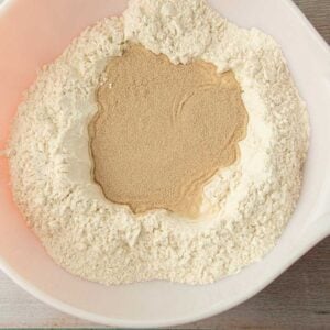 sprinkling yeast over water in a bowl of flour
