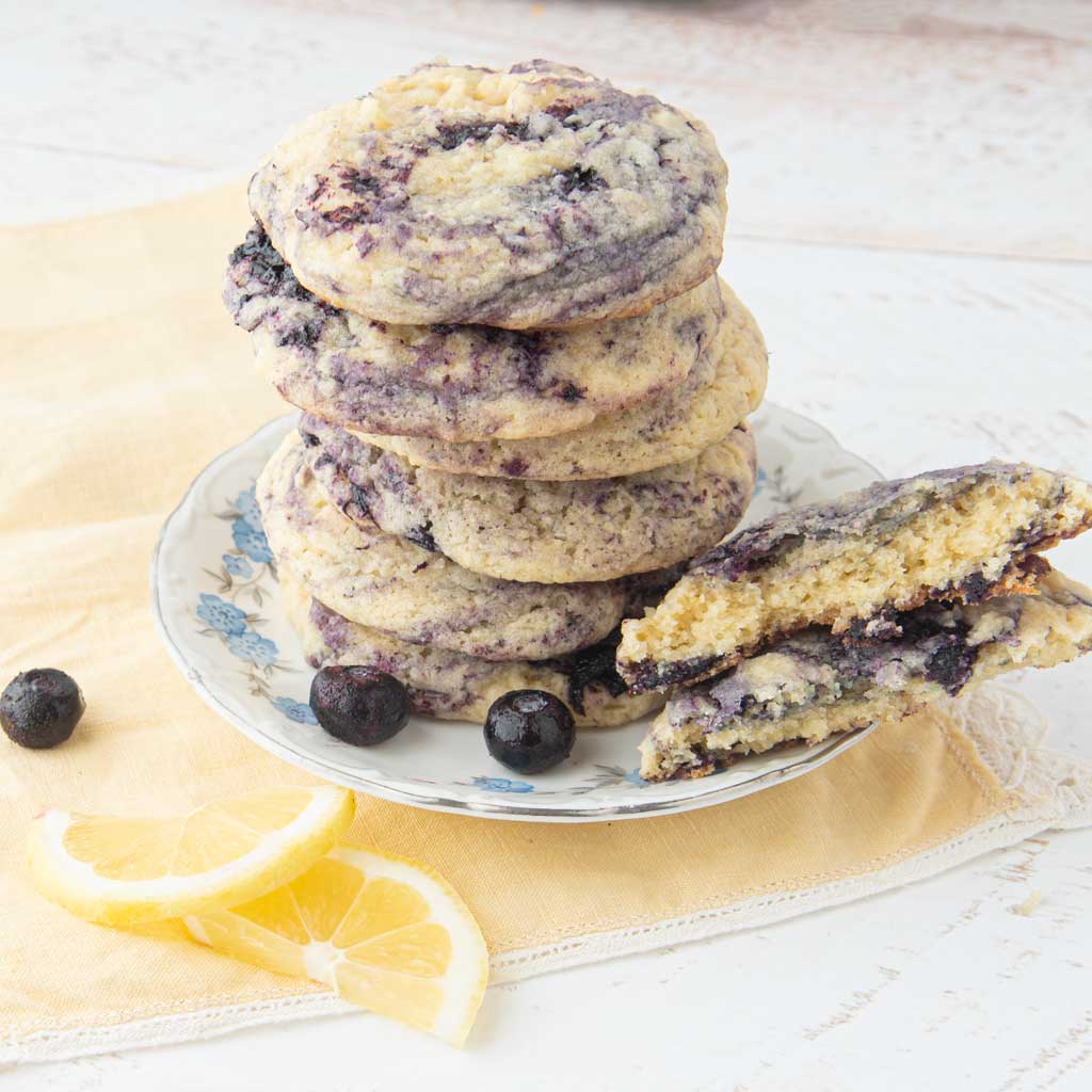 stack of lemon blueberry cookies next to lemon slices and blueberries