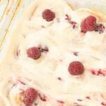 pan of lemon raspberry rolls frosted with lemon cream cheese frosting with raspberries on top, text overlay