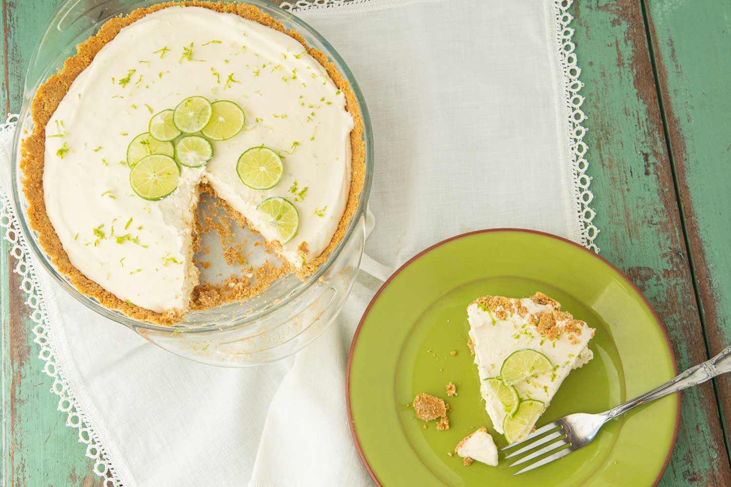 whole frozen key lime pie and pie piece out of whole pie on green plate