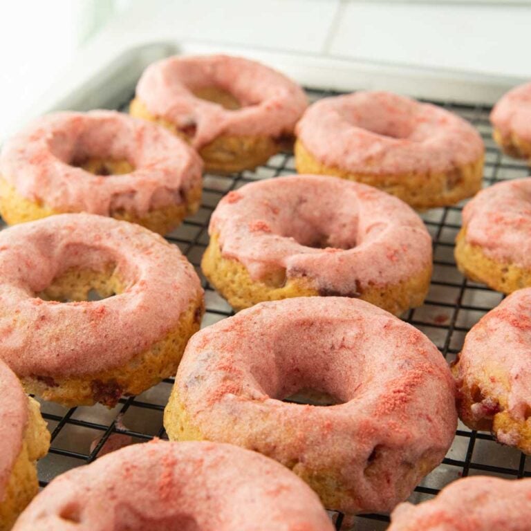 strawberry glazed donuts on wire rack, from eye level
