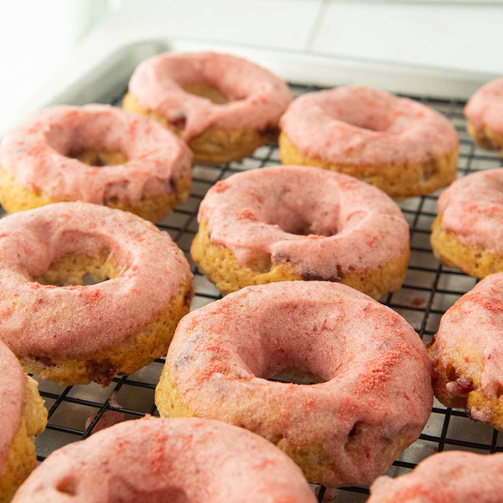 strawberry glazed donuts on wire rack, from eye level
