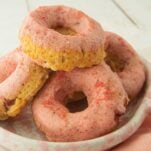 stack of strawberry donuts in plate on pink napkin