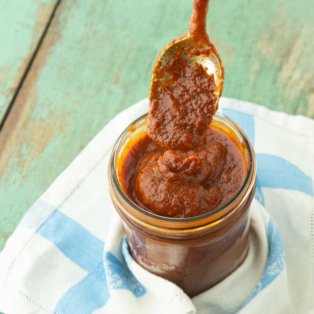 spoon with bbq sauce falling into jar