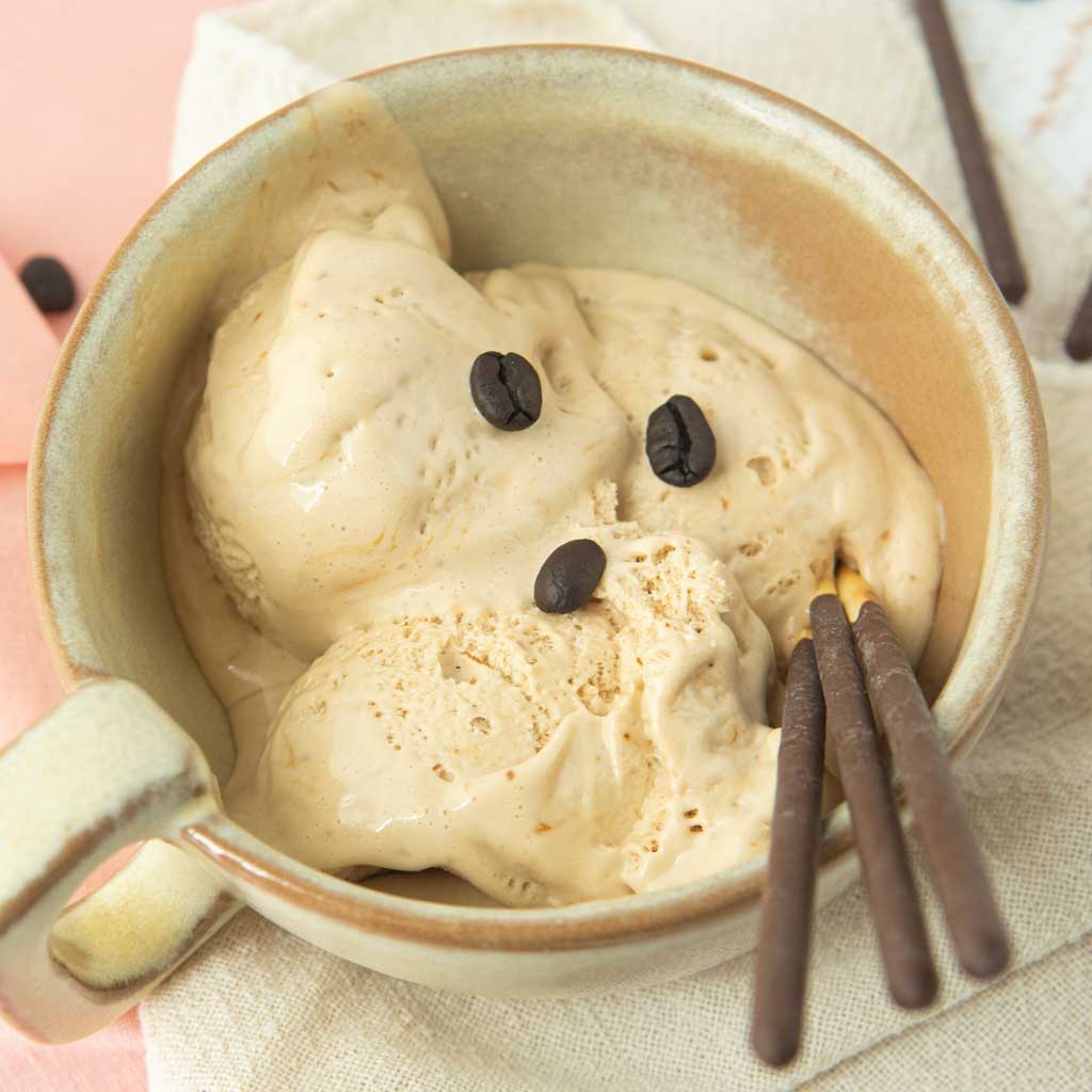 closeup of coffee ice cream in beige cup with chocolate Pocky sticks