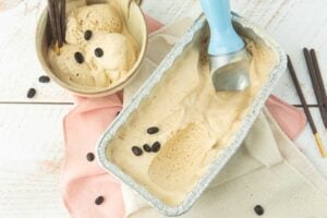 coffee ice cream in beige cup with chocolate Pocky sticks, ice cream scoop in loaf pan of coffee ice cream