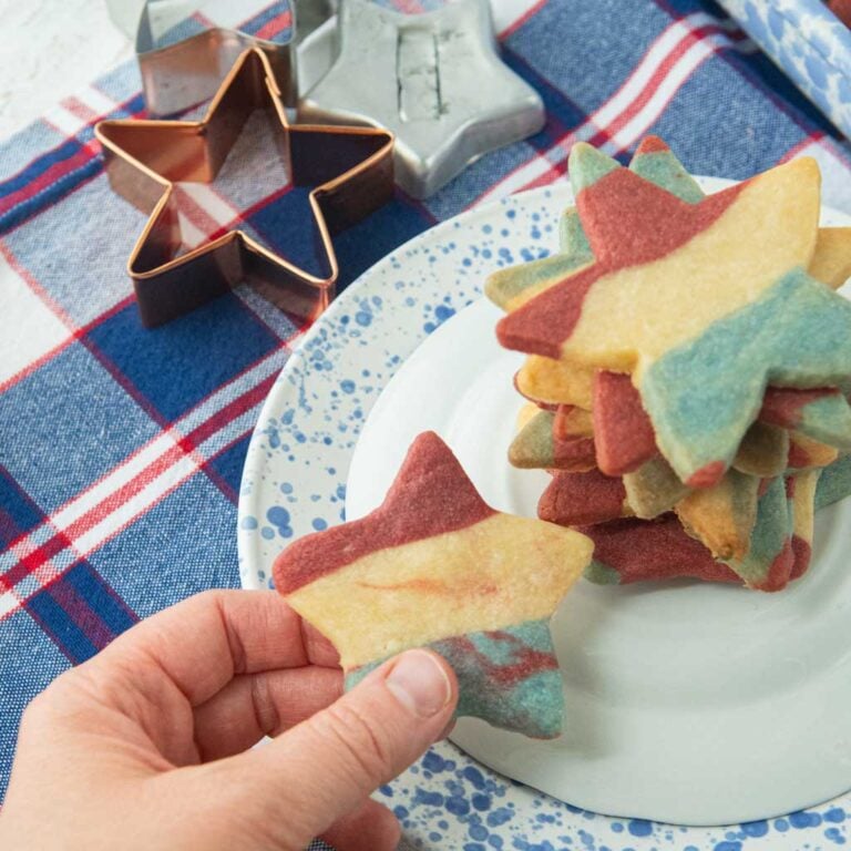 star cookie cutters, red white and blue tablecloth, red white and blue star cookies on plate, hand holding star cookie