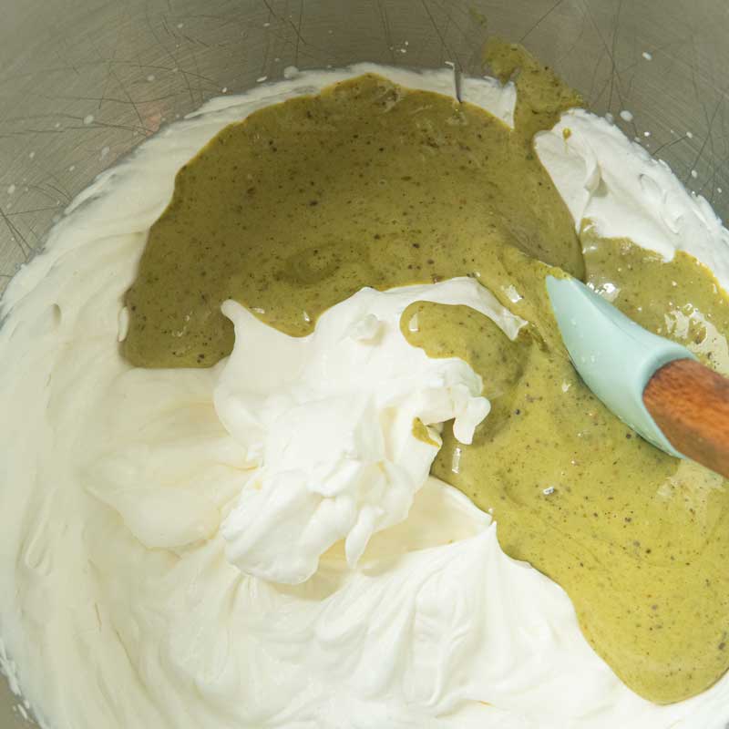 adding pistachio cream to heavy cream
