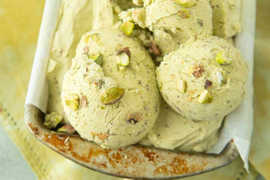 closeup of pistachio ice cream in loaf pan with chopped pistachios