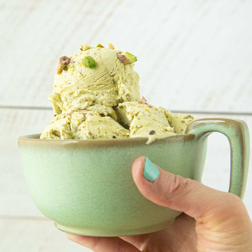 hand holding mug of pistachio ice cream