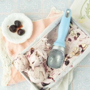 scoops of cherry ice cream in loaf pan, bowl of cherries, pink towel, ice cream scoop