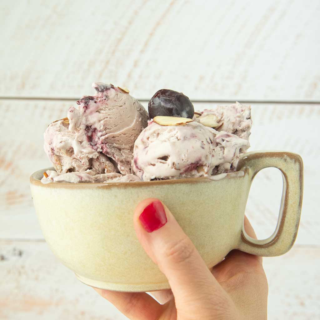 hand holding mug of cherry ice cream