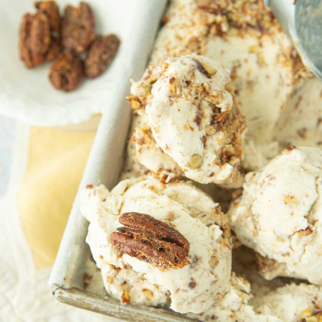 closeup of scoops of butter pecan ice cream with whole candied pecans