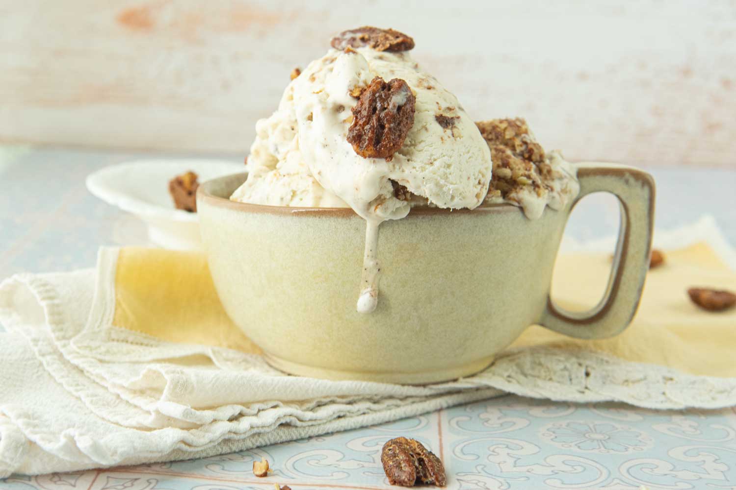 cup of candied pecan ice cream with whole candied pecans with drip down the side