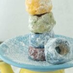 stack of rainbow cake donuts on plate on teapot, text overlay