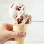 hand holding cone filled with strawberry cheesecake ice cream