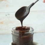 fudge sauce dripping into jar from spoon