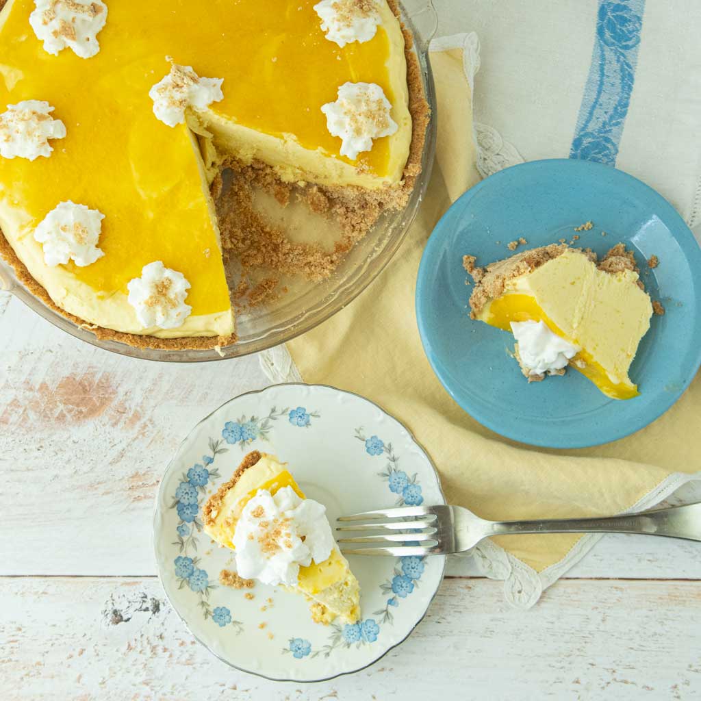 slices of mango pie on plates, fork, whole mango pie with slices cut out of it