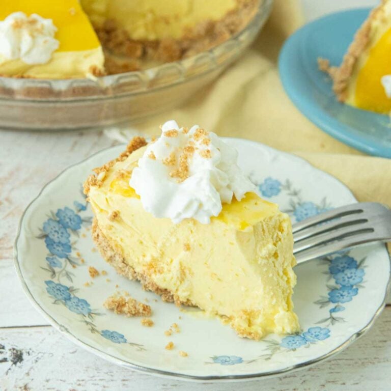slice of mango pie on plate, fork, whole pie in background