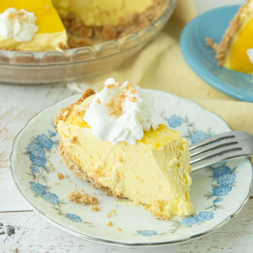 slice of mango pie on plate, fork, whole pie in background