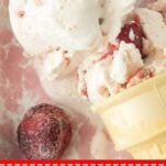closeup of cone of strawberry cheesecake ice cream and whole strawberries in pink and white dish, text overlay