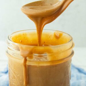 dulce de leche falling off spoon into jar of dulce de leche