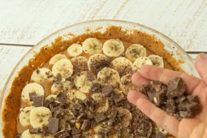 scattering toffee over sliced bananas in a pie