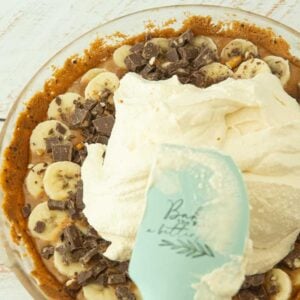 spreading whipped cream over bananas in pie